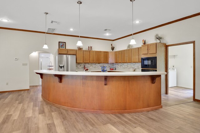 210 Harbor Run Dr, Coldspring, TX 77331 - kitchen featuring stainless steel refrigerator with ice dispenser, black microwave, tasteful backsplash, light countertops, and ornamental molding