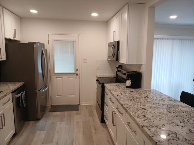 12907 Trail Hollow Dr Unit 2907, Houston, TX 77079 - kitchen with stainless steel appliances, light wood-style flooring, white cabinets, light stone counters, and backsplash