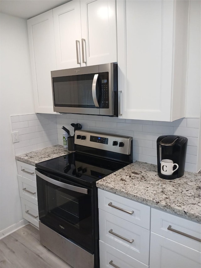 12907 Trail Hollow Dr Unit 2907, Houston, TX 77079 - kitchen with stainless steel appliances, white cabinetry, tasteful backsplash, light wood-type flooring, and light stone countertops