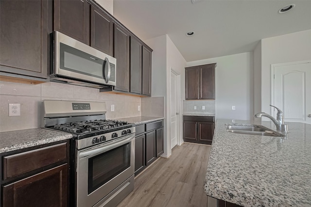 15502 Islandview Ln, Houston, TX 77053 - kitchen featuring appliances with stainless steel finishes, a sink, light stone countertops, light wood-style flooring, and dark brown cabinets