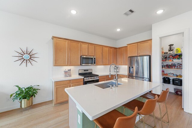 12526 Sabine Point Dr, Humble, TX 77346 - kitchen with stainless steel appliances, a sink, light wood-style floors, a breakfast bar, and recessed lighting