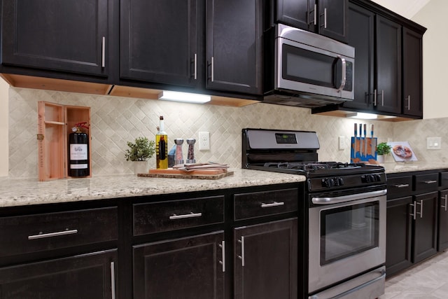 3864 Oakmist Bend Ln, Spring, TX 77386 - kitchen with stainless steel appliances, dark cabinetry, light stone countertops, and tasteful backsplash