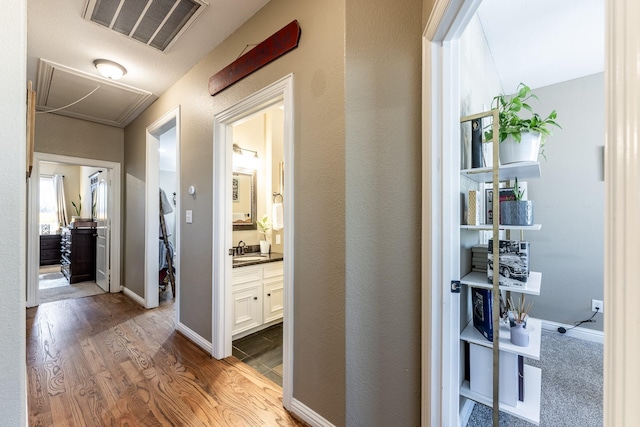 717 Overbrook, Huntsville, TX 77340 - corridor featuring a sink, wood finished floors, attic access, and baseboards