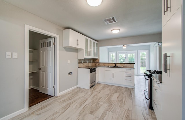 4621 W 43rd St, Houston, TX 77092 - kitchen featuring appliances with stainless steel finishes, a sink, dark countertops, glass insert cabinets, and white cabinetry