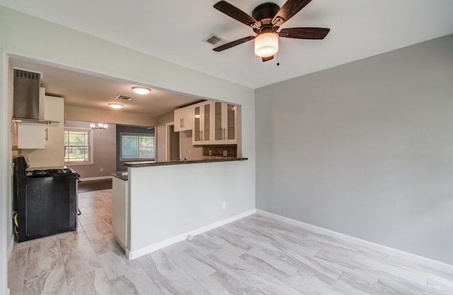 4621 W 43rd St, Houston, TX 77092 - kitchen featuring wall chimney range hood, gas range, white cabinets, dark countertops, and glass insert cabinets