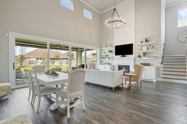 25007 Coperti Ln, Spring, TX 77386 - dining area featuring ornamental molding, a towering ceiling, dark wood-type flooring, stairway, and a lit fireplace