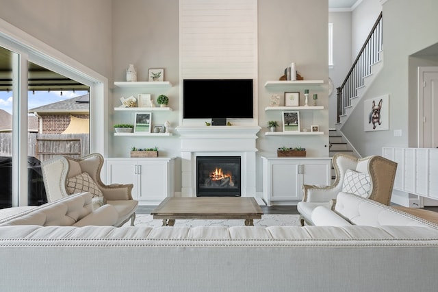 25007 Coperti Ln, Spring, TX 77386 - living room featuring healthy amount of natural light, built in shelves, a glass covered fireplace, a towering ceiling, and ornamental molding
