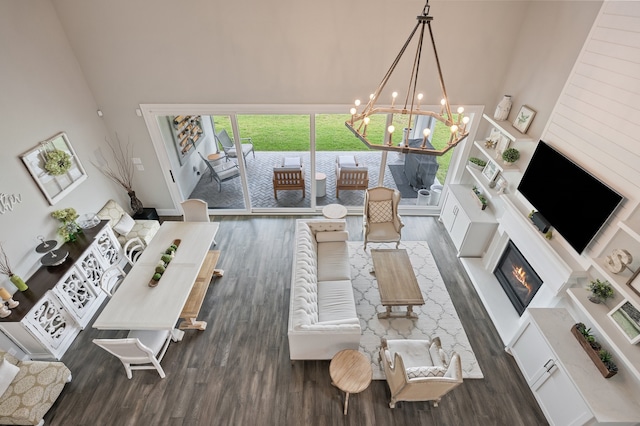 25007 Coperti Ln, Spring, TX 77386 - living room featuring a high ceiling, wood finished floors, a chandelier, a glass covered fireplace, and baseboards