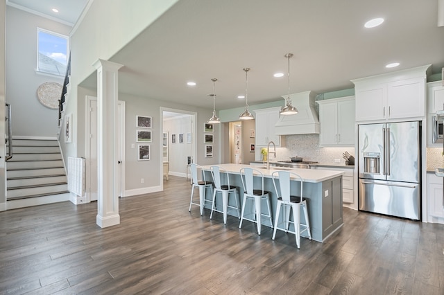 25007 Coperti Ln, Spring, TX 77386 - kitchen with stainless steel appliances, custom exhaust hood, an island with sink, a breakfast bar, and backsplash