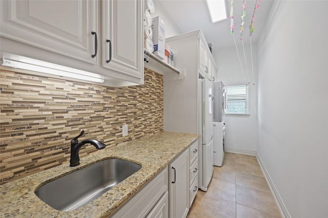 5451 Harvest Oak Landing Dr, Spring, TX 77386 - kitchen featuring a sink, tasteful backsplash, white cabinetry, light tile patterned flooring, and baseboards