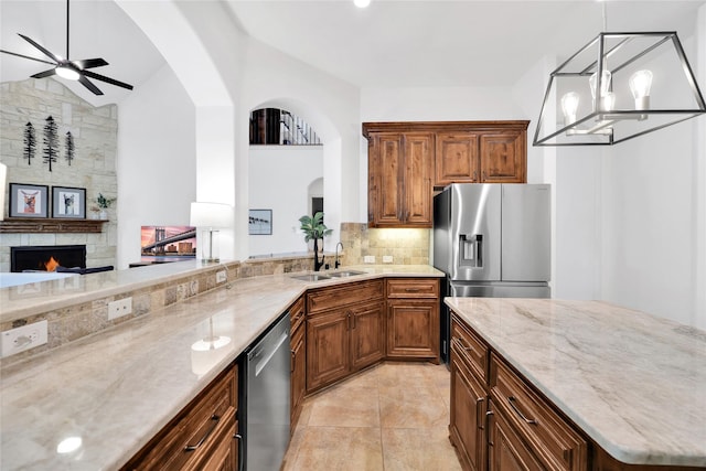 5451 Harvest Oak Landing Dr, Spring, TX 77386 - kitchen featuring appliances with stainless steel finishes, a sink, light stone counters, decorative backsplash, and arched walkways