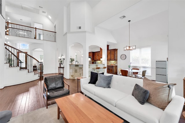 5451 Harvest Oak Landing Dr, Spring, TX 77386 - living room featuring arched walkways, hardwood / wood-style floors, healthy amount of natural light, high vaulted ceiling, and a chandelier