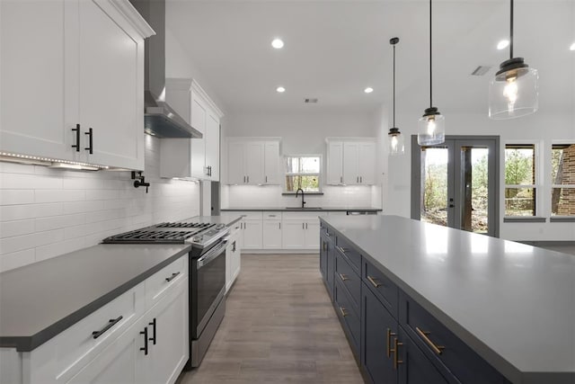 1806 Athens Dr, Roman Forest, TX 77357 - kitchen with stainless steel range with gas stovetop, white cabinetry, recessed lighting, wall chimney range hood, and tasteful backsplash
