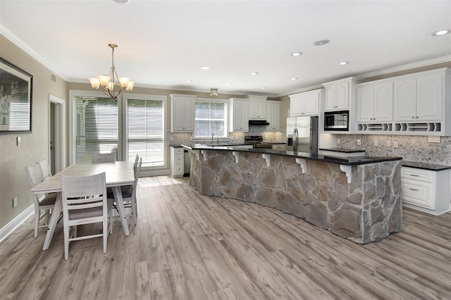 27140 Fm 365, Beaumont, TX 77705 - kitchen featuring appliances with stainless steel finishes, ornamental molding, a chandelier, decorative backsplash, and light wood finished floors