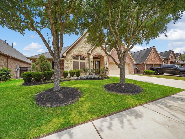 5411 Cedar Elm Ln, Fulshear, TX 77441 - view of front of house with a front yard, driveway, stone siding, and a garage