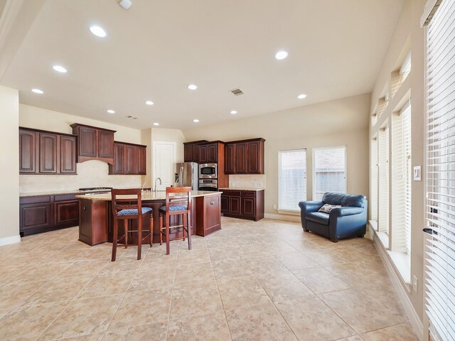 5411 Cedar Elm Ln, Fulshear, TX 77441 - kitchen featuring stainless steel appliances, light countertops, open floor plan, a breakfast bar area, and a kitchen island with sink