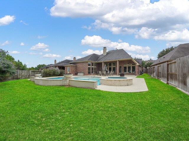 5411 Cedar Elm Ln, Fulshear, TX 77441 - back of property featuring an in-ground hot tub, brick siding, a patio area, and a chimney
