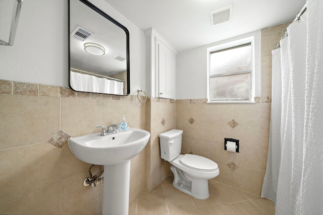 12310 New Brunswick Dr, Houston, TX 77089 - bathroom with tile walls, toilet, tile patterned floors, a sink, and a wainscoted wall