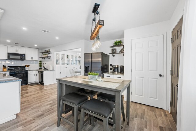 729 Kyle St, Angleton, TX 77515 - kitchen with black appliances, open shelves, light wood-style floors, white cabinets, and recessed lighting