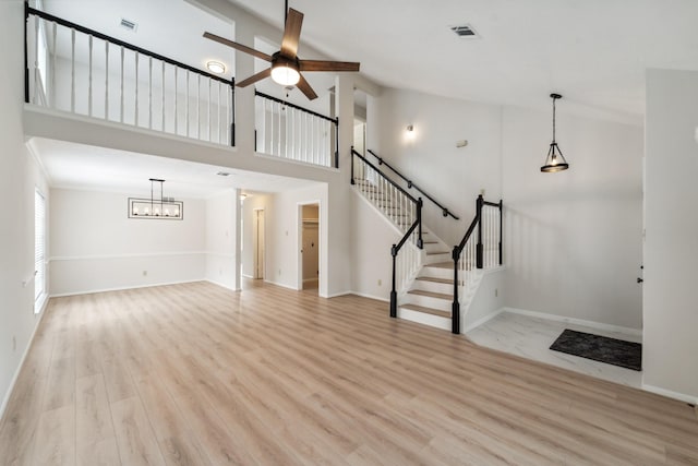 13038 Skymeadow Dr, Houston, TX 77082 - unfurnished living room with ceiling fan, light wood finished floors, stairs, high vaulted ceiling, and baseboards