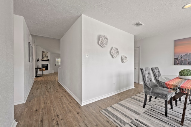 3247 Bolton Gardens Dr, Houston, TX 77066 - dining room with wood finished floors, a textured ceiling, baseboards, and a large fireplace