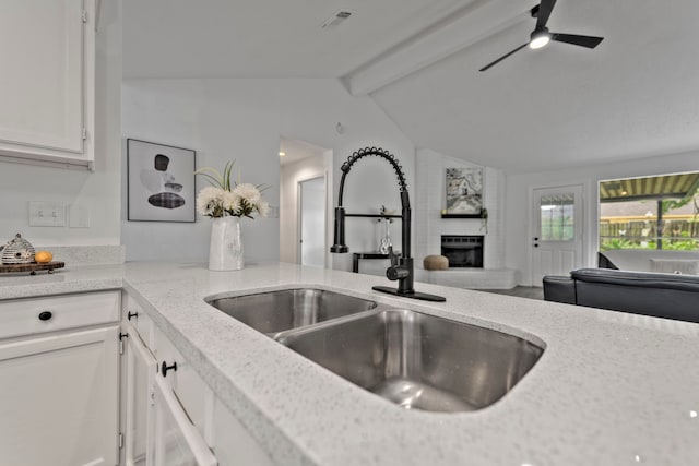 3247 Bolton Gardens Dr, Houston, TX 77066 - kitchen featuring a sink, a brick fireplace, white cabinetry, and a ceiling fan