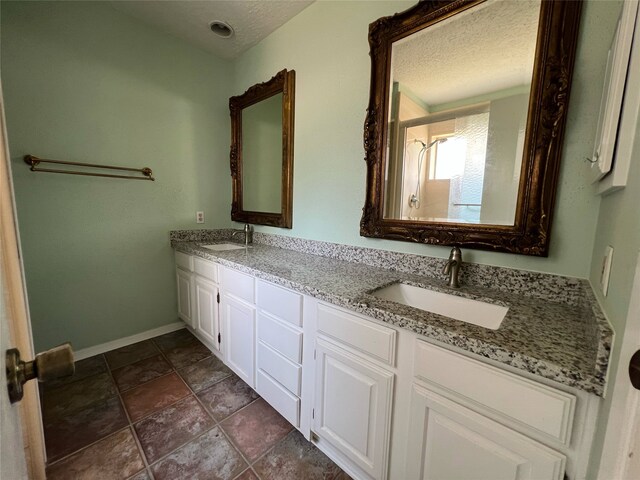 2134 Collingsfield Dr, Sugar Land, TX 77478 - bathroom with a textured ceiling, double vanity, baseboards, and stone finish floors