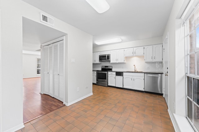 10345 Longmont Dr, Houston, TX 77042 - kitchen with stainless steel appliances, a sink, white cabinetry, dark countertops, and tasteful backsplash