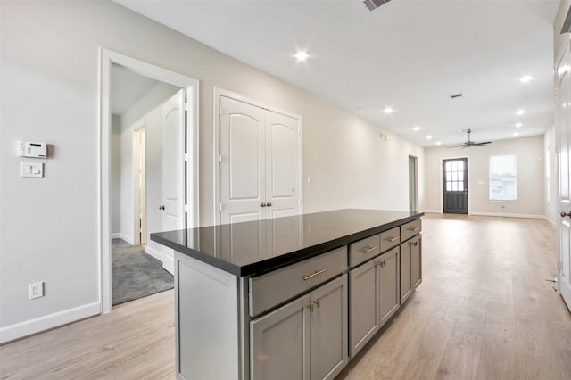 2517 S Houston Ave, Pearland, TX 77581 - kitchen with gray cabinets, dark countertops, light wood-type flooring, a kitchen island, and a ceiling fan