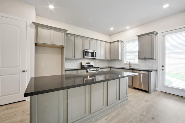 2517 S Houston Ave, Pearland, TX 77581 - kitchen featuring appliances with stainless steel finishes, gray cabinetry, dark countertops, a kitchen island, and decorative backsplash
