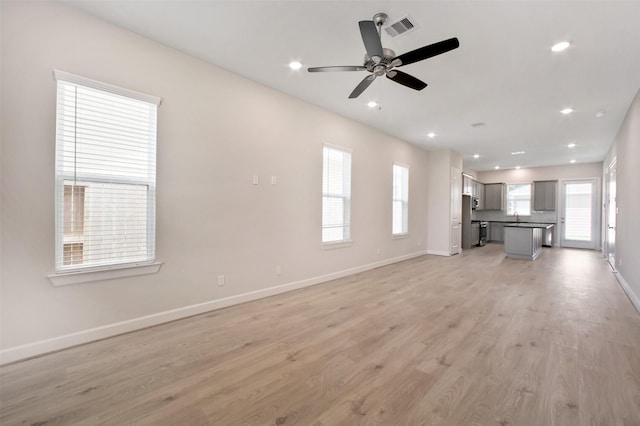 2517 S Houston Ave, Pearland, TX 77581 - unfurnished living room featuring baseboards, ceiling fan, recessed lighting, light wood-style flooring, and a sink
