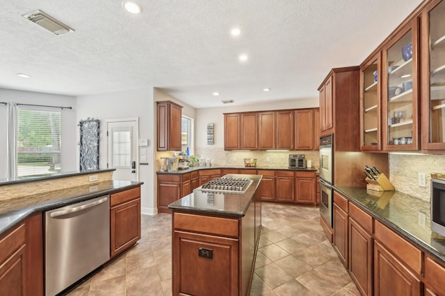 12106 Via Chianti Ct, Cypress, TX 77429 - kitchen featuring appliances with stainless steel finishes, tasteful backsplash, a kitchen island, recessed lighting, and glass insert cabinets
