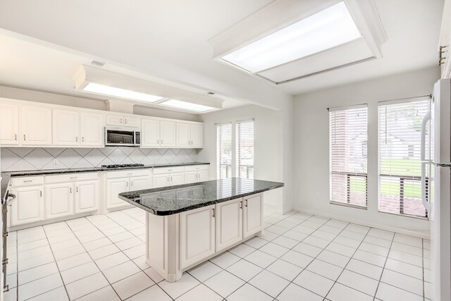 3920 Blackberry Ln, Port Arthur, TX 77642 - kitchen featuring gas stovetop, freestanding refrigerator, white cabinets, tasteful backsplash, and a kitchen island
