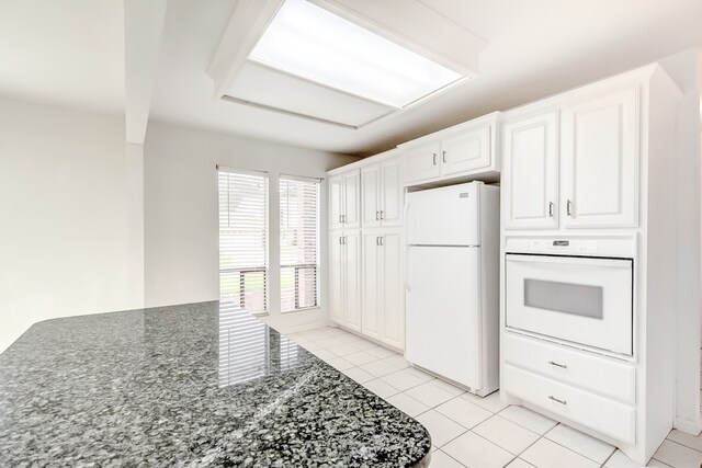 3920 Blackberry Ln, Port Arthur, TX 77642 - kitchen featuring white appliances, dark stone countertops, and white cabinetry