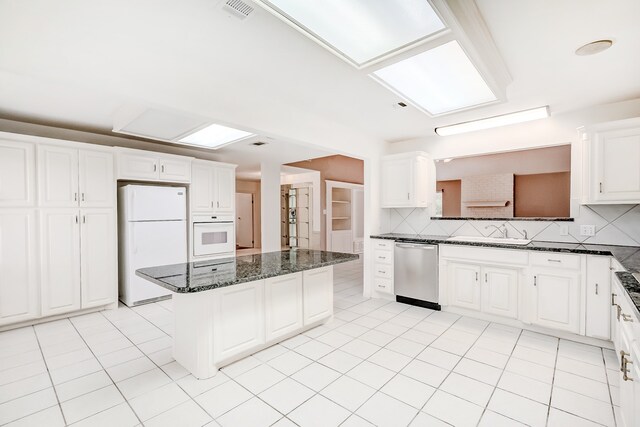 3920 Blackberry Ln, Port Arthur, TX 77642 - kitchen featuring white appliances, a kitchen island, a sink, backsplash, and white cabinets