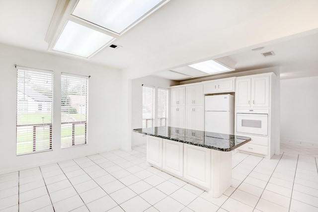 3920 Blackberry Ln, Port Arthur, TX 77642 - kitchen with white appliances, white cabinetry, dark stone counters, a kitchen island, and light tile patterned floors