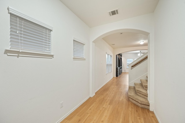 2827 Arica Ln, Spring, TX 77373 - hallway featuring arched walkways, light wood-type flooring, stairs, and baseboards