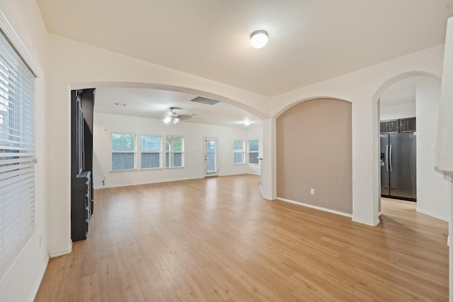 2827 Arica Ln, Spring, TX 77373 - unfurnished living room featuring ceiling fan, light wood-style floors, arched walkways, and baseboards