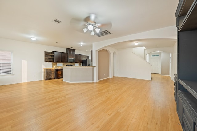 2827 Arica Ln, Spring, TX 77373 - unfurnished living room featuring ceiling fan, arched walkways, light wood-type flooring, and baseboards