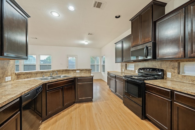 2827 Arica Ln, Spring, TX 77373 - kitchen with black appliances, a sink, light wood-style floors, backsplash, and dark brown cabinetry