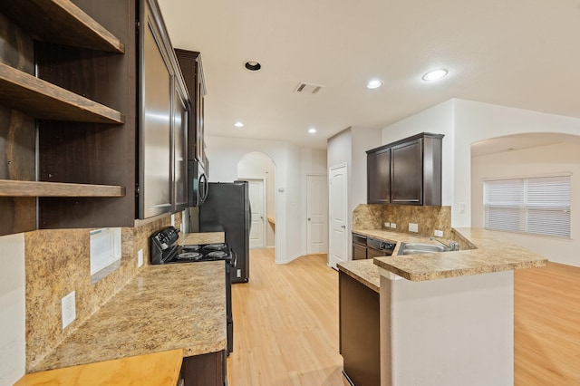2827 Arica Ln, Spring, TX 77373 - kitchen with arched walkways, black electric range, tasteful backsplash, dark brown cabinetry, and light countertops