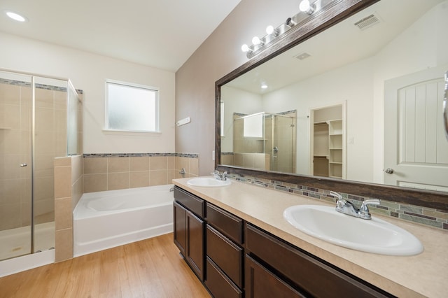 2827 Arica Ln, Spring, TX 77373 - full bathroom featuring a stall shower, a bath, wood finished floors, double vanity, and a spacious closet