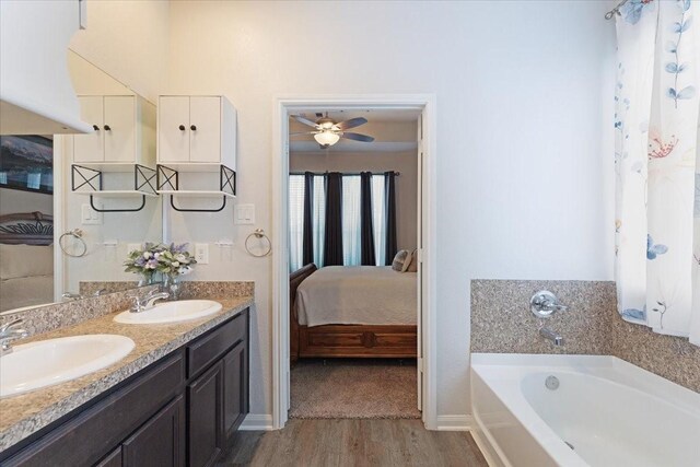 1685 Rd 5102, Cleveland, TX 77327 - ensuite bathroom featuring a bath, wood finished floors, double vanity, baseboards, and ceiling fan