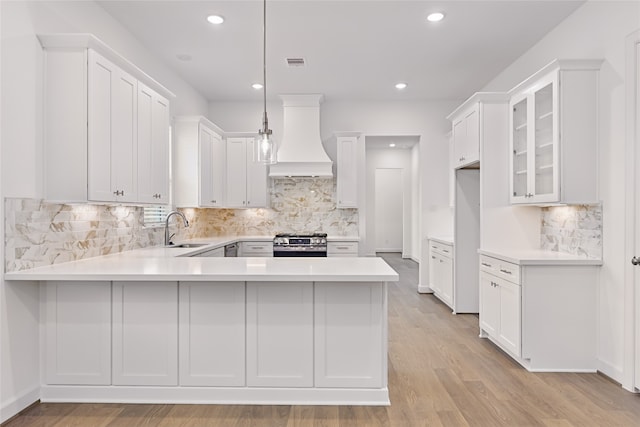 2516 S Grand Ave, Pearland, TX 77581 - kitchen with custom range hood, stainless steel range with gas cooktop, a peninsula, decorative backsplash, and light countertops