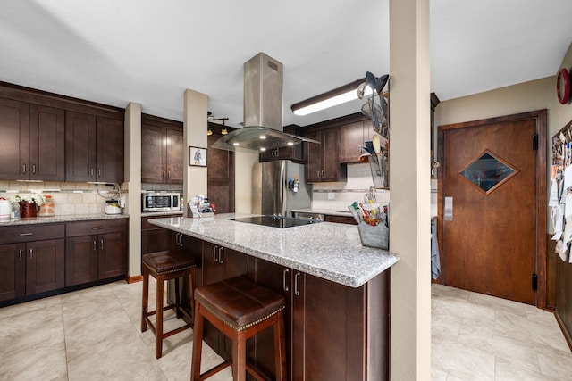 14907 River Oaks Dr, East Bernard, TX 77435 - kitchen with island range hood, appliances with stainless steel finishes, backsplash, and dark brown cabinets