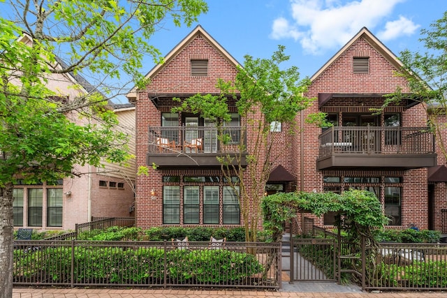 26 Riva Row, The Woodlands, TX 77380 - view of front of property with a fenced front yard, a balcony, a gate, and brick siding