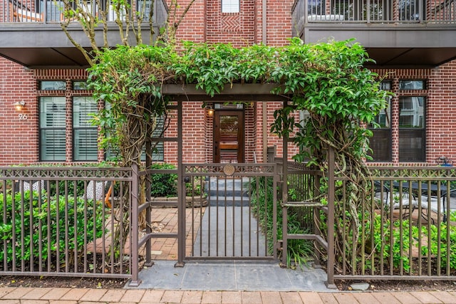 26 Riva Row, The Woodlands, TX 77380 - doorway to property featuring brick siding, a gate, and a balcony