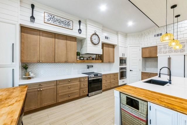 209 Horse Shoe Trl, Angleton, TX 77515 - kitchen featuring built in appliances, butcher block countertops, tasteful backsplash, a sink, and decorative light fixtures