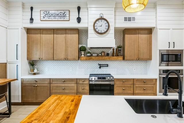 209 Horse Shoe Trl, Angleton, TX 77515 - kitchen featuring stainless steel appliances, a sink, butcher block countertops, backsplash, and ventilation hood