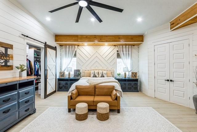209 Horse Shoe Trl, Angleton, TX 77515 - bedroom featuring a barn door, a closet, beamed ceiling, light wood-style flooring, and multiple windows